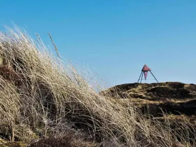 a windmill on top of a hill with tall grass at 6 person holiday home in Bedsted Thy-By Traum in Bedsted Thy