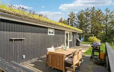 a wooden deck with a table and chairs and a grill at 3 Bedroom Cozy Home In Blokhus in Blokhus