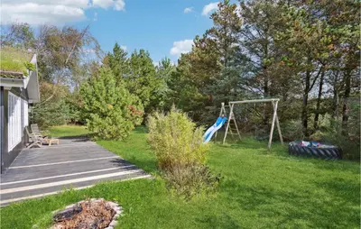 a yard with a swing in the grass at 3 Bedroom Cozy Home In Blokhus in Blokhus