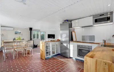 a kitchen with white cabinets and a table and chairs at 3 Bedroom Cozy Home In Blokhus in Blokhus