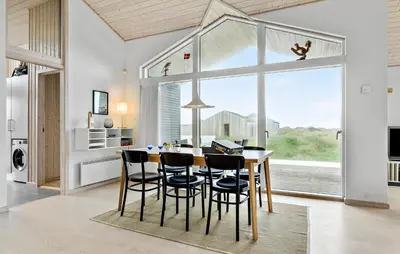 a kitchen with a table and chairs and a large window at Awesome Home In Løkken With Kitchen in Løkken