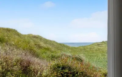 a grassy hill with the ocean in the background at Awesome Home In Løkken With Kitchen in Løkken