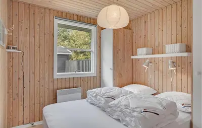 a bedroom with wooden walls and a bed with white sheets at 3 Bedroom Awesome Home In Saltum in Saltum