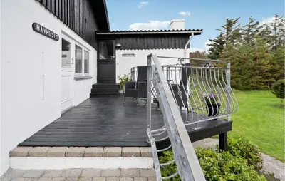 a wooden porch with a bench in front of a house at Stunning Home In Blokhus in Blokhus