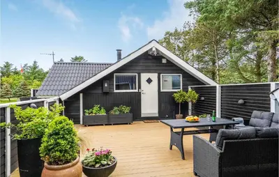 a black house with a patio with a table at Nice Home In Løkken With Kitchen in Løkken