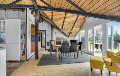 a dining room and living room with a table and chairs at Nice Home In Løkken With Kitchen in Løkken