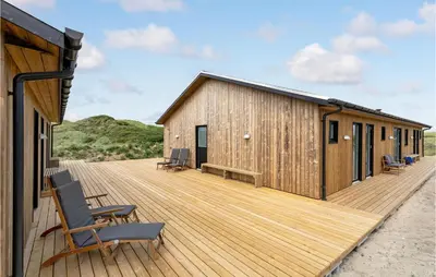 a wooden deck with chairs and a building at Nice Home In Løkken With Sauna in Løkken