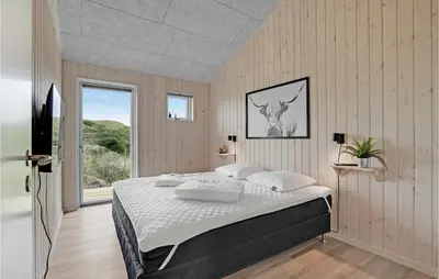 a bedroom with a large bed and a window at Nice Home In Løkken With Sauna in Løkken