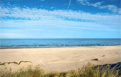 a sandy beach with the ocean in the background at Nice Home In Løkken With Sauna in Løkken