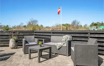 a patio with chairs and a table and a flag at Gorgeous Home In Blokhus With Sauna in Blokhus