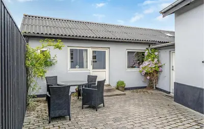 a patio with a table and chairs in front of a house at Gorgeous Apartment In Blokhus With Wifi in Blokhus