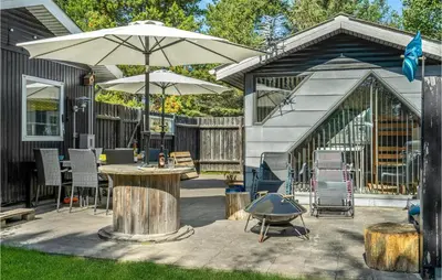 a patio with a table and an umbrella and chairs at 3 Bedroom Pet Friendly Home In Blokhus in Blokhus
