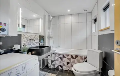 a bathroom with a toilet and a sink and a tub at 3 Bedroom Pet Friendly Home In Blokhus in Blokhus