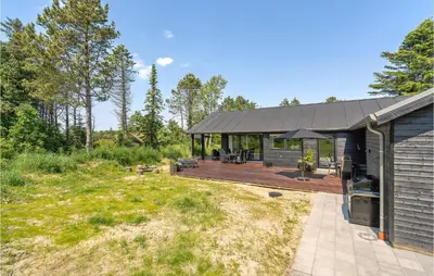 a home with a deck and a house at 4 Bedroom Amazing Home In Blokhus in Blokhus