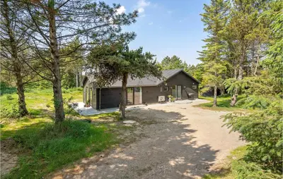 a house in the woods with a dirt road in front at 4 Bedroom Amazing Home In Blokhus in Blokhus