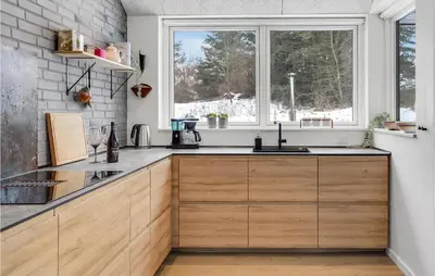 a kitchen with wooden cabinets and a window at 4 Bedroom Amazing Home In Blokhus in Blokhus
