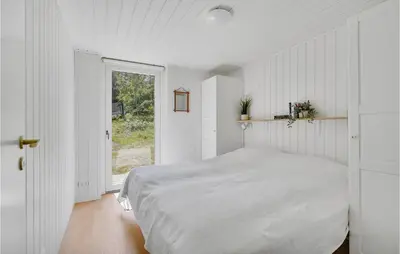 a white bedroom with a bed and a window at 4 Bedroom Amazing Home In Blokhus in Blokhus