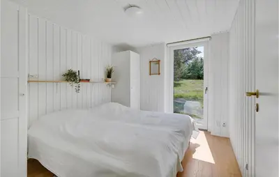 a white bedroom with a bed and a window at 4 Bedroom Amazing Home In Blokhus in Blokhus
