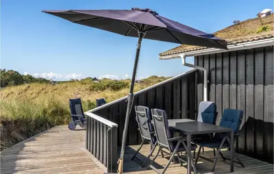 a table and chairs on a deck with an umbrella at 5 Bedroom Stunning Home In Blokhus in Blokhus