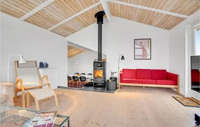 a living room with a red couch and a wood stove at 5 Bedroom Stunning Home In Blokhus in Blokhus