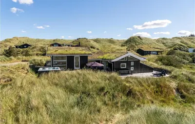a house with a grass roof on top of a hill at 5 Bedroom Stunning Home In Blokhus in Blokhus