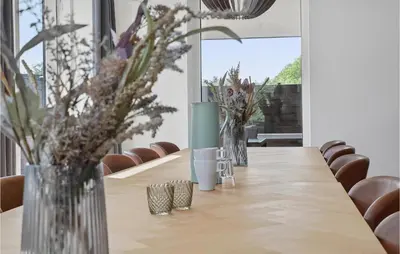 a long wooden table with vases of flowers on it at Stunning Home In Blokhus With Kitchen in Blokhus