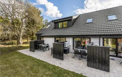 a house with a patio with tables and chairs at 2 Bedroom Cozy Apartment In Blokhus in Blokhus