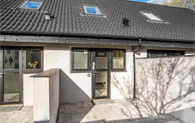 a white building with glass doors and a gray roof at 2 Bedroom Cozy Apartment In Blokhus in Blokhus
