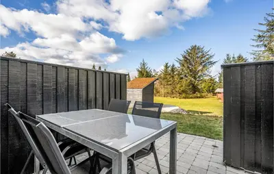 a table and chairs on a patio with a fence at 2 Bedroom Cozy Apartment In Blokhus in Blokhus