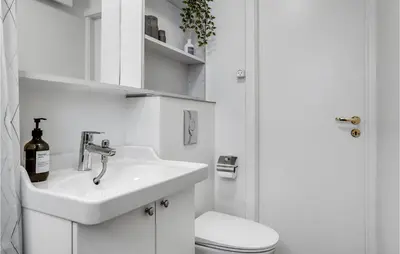 a white bathroom with a sink and a toilet at 2 Bedroom Cozy Apartment In Blokhus in Blokhus