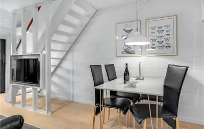 a dining room with a table and chairs and a tv at 2 Bedroom Cozy Apartment In Blokhus in Blokhus