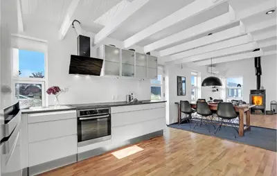 a kitchen with white cabinets and a table with chairs at 3 Bedroom Gorgeous Home In Blokhus in Blokhus