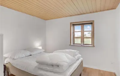 a bedroom with a bed with white sheets and a window at 3 Bedroom Stunning Home In Pandrup in Pandrup