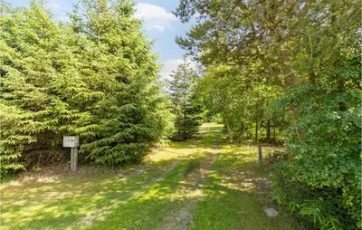 a path through a forest with trees and a sign at 3 Bedroom Gorgeous Home In Pandrup in Pandrup