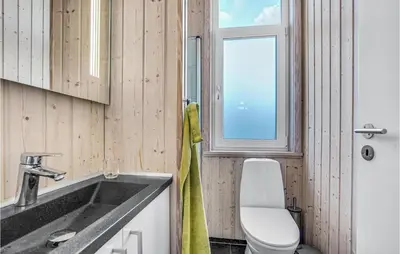 a bathroom with a sink and a toilet and a window at Nice Home In Blokhus With Kitchen in Blokhus
