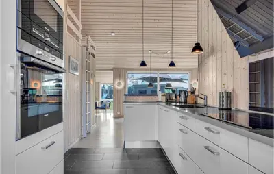 a kitchen with white cabinets and a large window at Nice Home In Blokhus With Kitchen in Blokhus