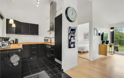 a kitchen with black cabinets and a clock on the wall at Amazing Home In Brovst With Kitchen in Brovst