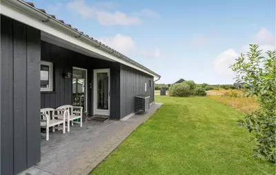 a black house with a patio and a lawn at Amazing Home In Brovst With Kitchen in Brovst