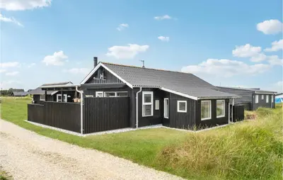 a black house on the side of a gravel road at Nice Home In Thisted With Kitchen in Thisted