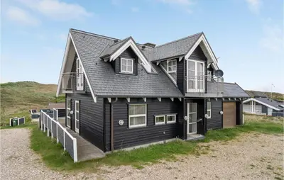 a black house with a gambrel roof on a beach at Lovely Home In Harboøre With Sauna in Harboør