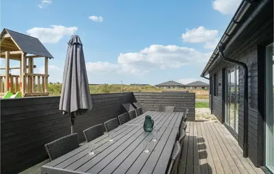 a wooden deck with a table and an umbrella at Lovely Home In Thisted With Sauna in Thisted