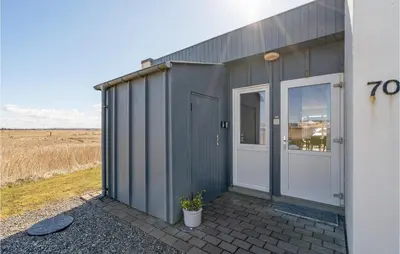 a gray building with a door and a field at Amazing Home In Vestervig With Sauna in Vestervig