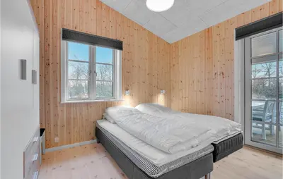 a bed in a room with wooden walls and windows at 3 Bedroom Cozy Home In Vemb in Vemb