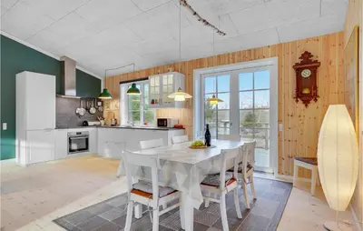 a kitchen with a table with chairs and a clock at 3 Bedroom Cozy Home In Vemb in Vemb