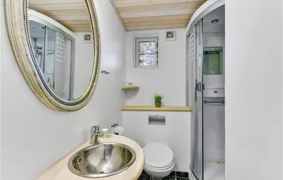a bathroom with a sink and a toilet and a mirror at Cozy Home In Vestervig With Sauna in Vestervig