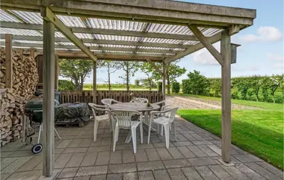 a patio with a table and chairs under a wooden pergola at Awesome Home In Vestervig With Wifi in Vestervig