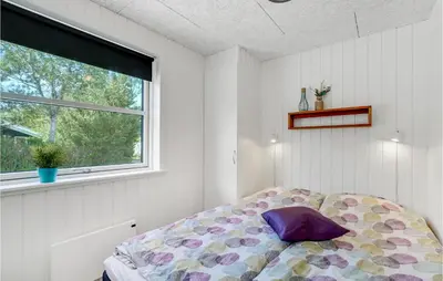 a bedroom with a bed with a purple pillow on it at Cozy Home In Thisted With Sauna in Thisted