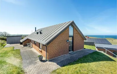 a house with a metal roof and the ocean in the background at Stunning Home In Struer With Wifi in Struer
