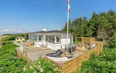 a home with a deck with chairs and a house at Lovely Home In Spøttrup With Wifi in Spottrup