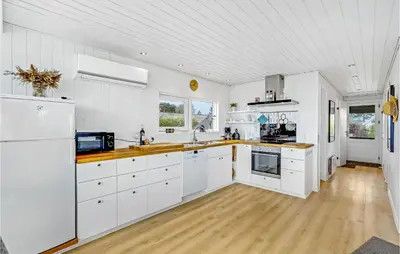 a kitchen with white cabinets and a wooden floor at Awesome Home In Øster Assels With Sauna in Øster Assels